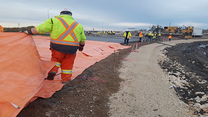 Workers tarping a paved roadway
