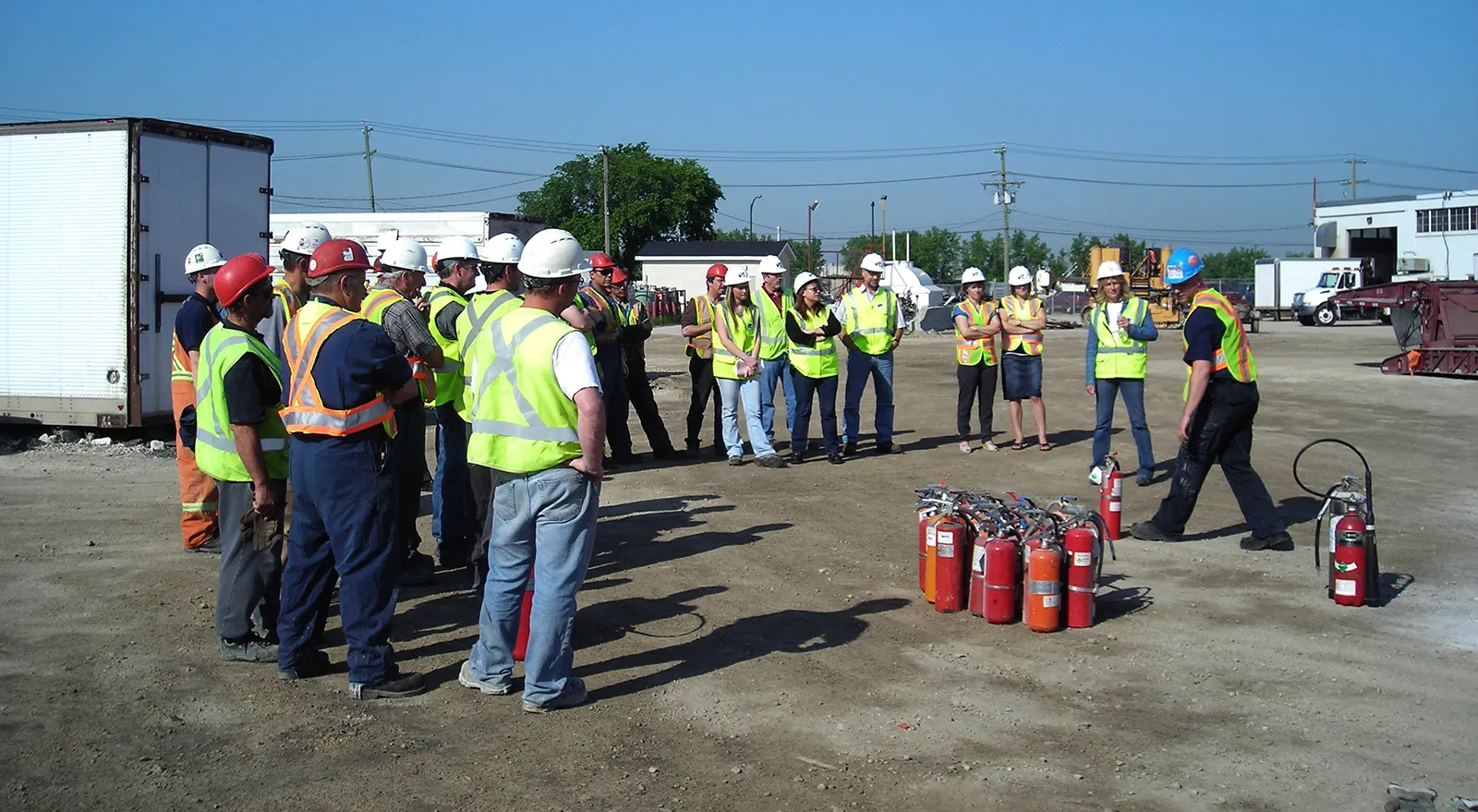 A group of construction workers watching a demonstration on fire extinguishers