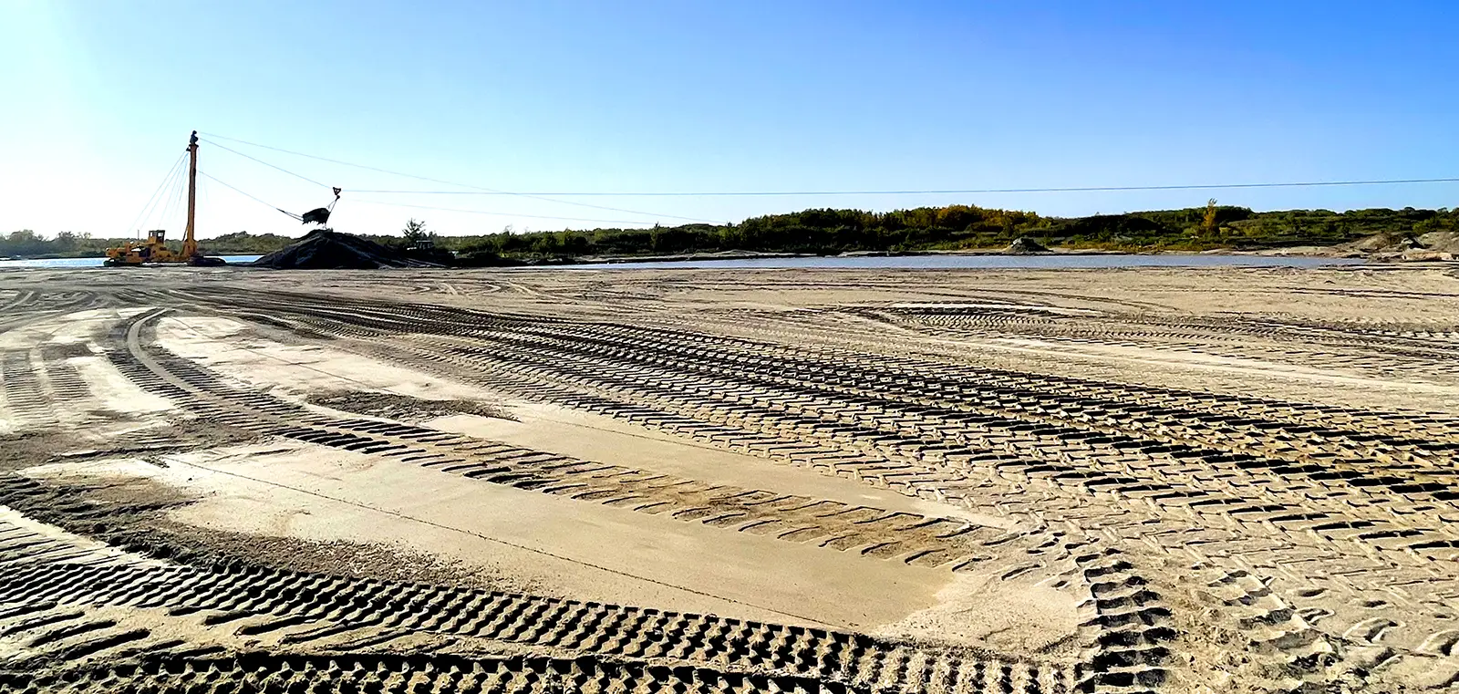 A landscape shot of a flattened construction site showing tread marks from heavy machinery.