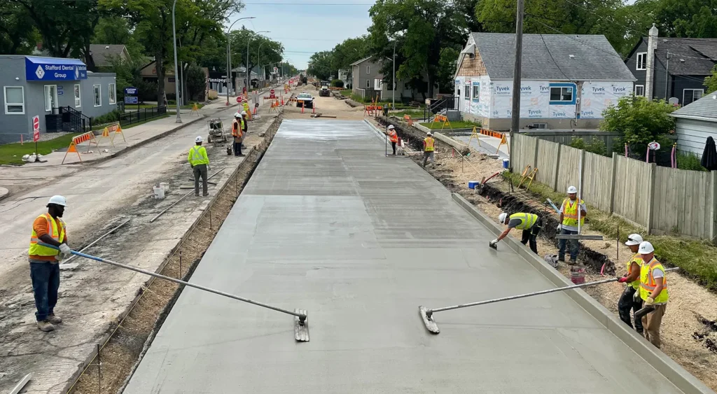 A long concrete roadway being screed by workers